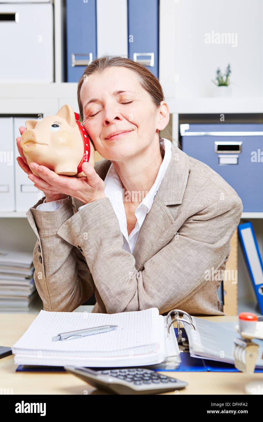 Senior business woman with piggy bank in her office at the desk Stock ...