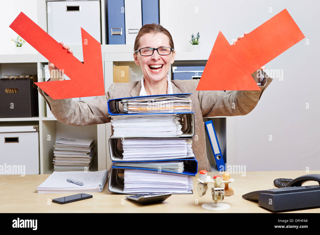 Happy business woman in office pointing arrows to stack of files Stock ...