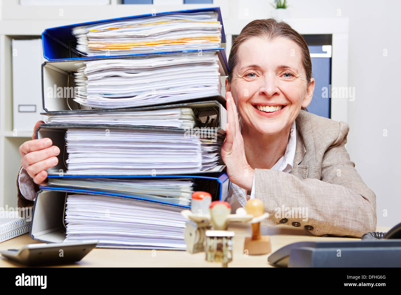 Happy business woman in office with a stack of files Stock Photo