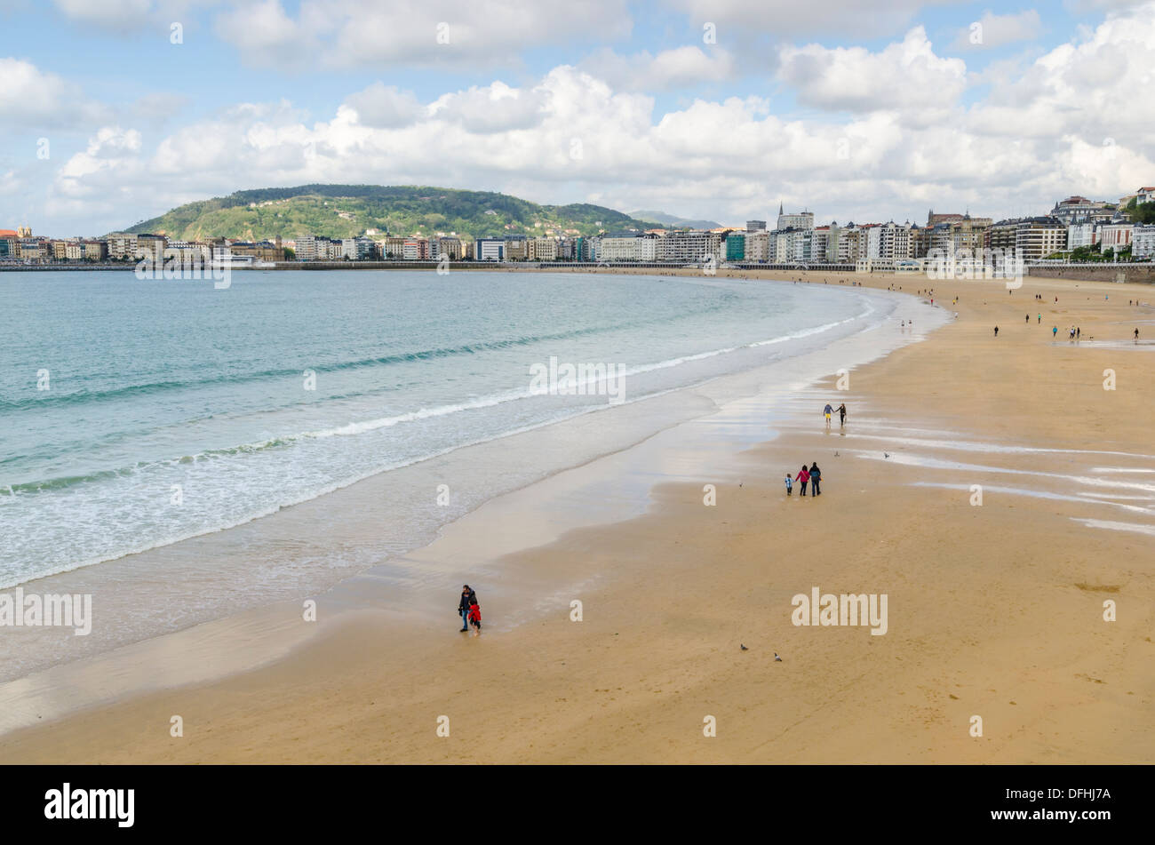 Beach walkers in Spring on the Playa de la Concha, San Sebastian, Spain Stock Photo