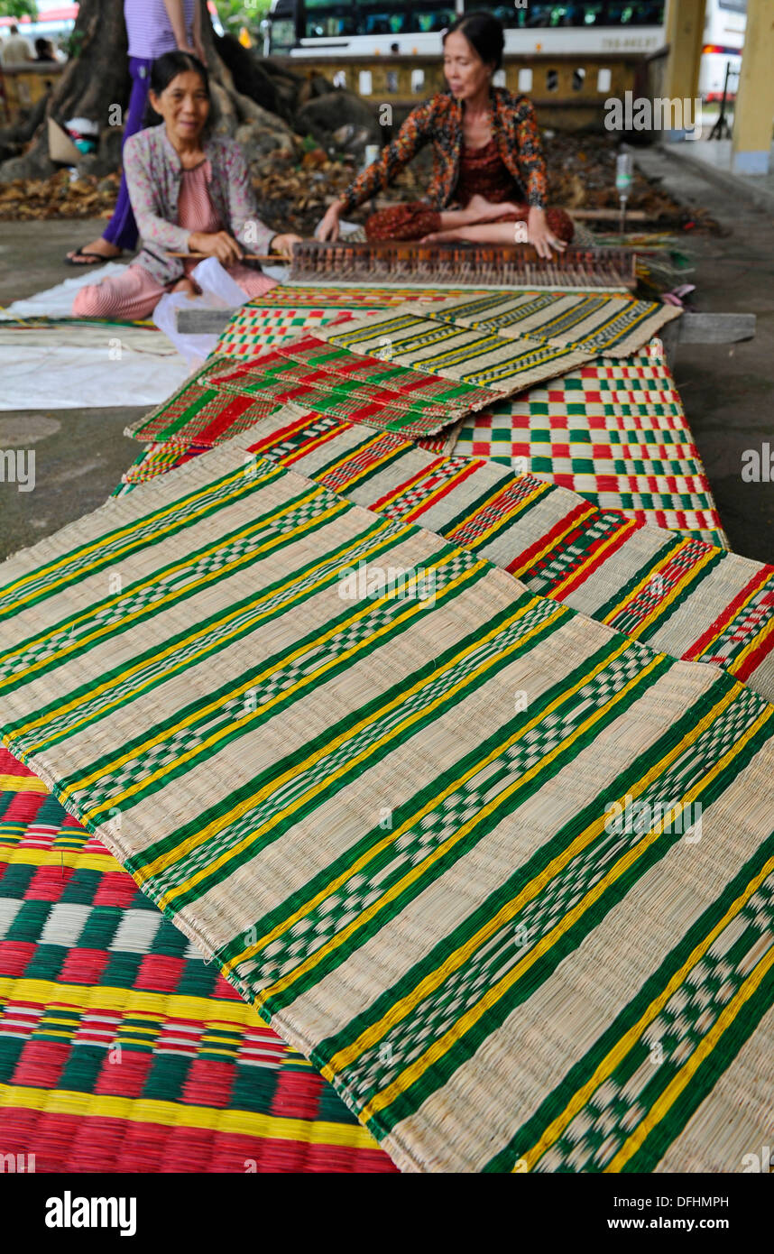 Elderly Vietnamese hand making colourful reed floor mats Stock Photo