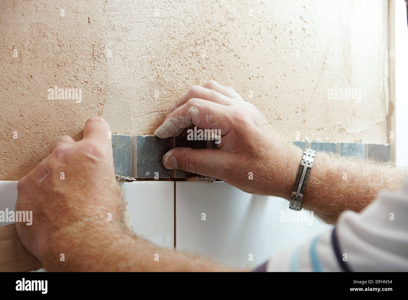 Tiler attaching tiles in a wet room / shower / bathroom on a newly plastered wall Stock Photo