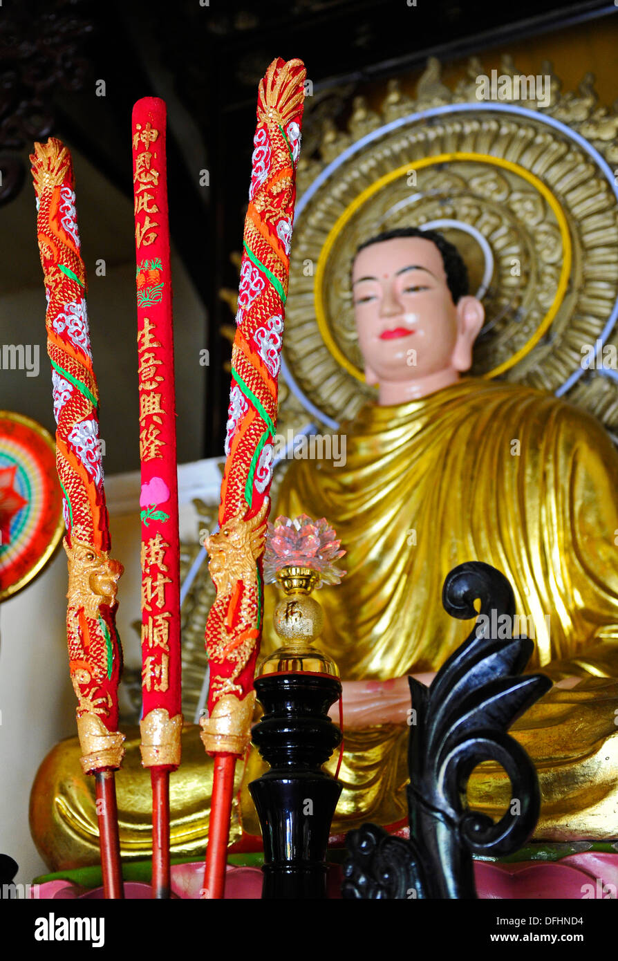 Colourful decorated candles in front of a sitting Buddha at a Buddhist