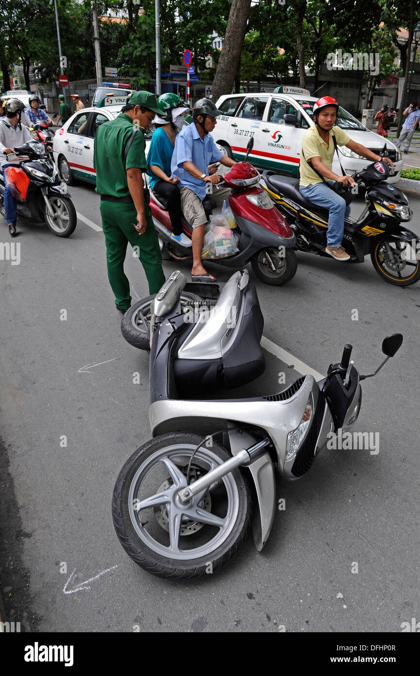 Vietnamese traffic police investigate a road traffic accident involving a motorbike on a busy street. Stock Photo