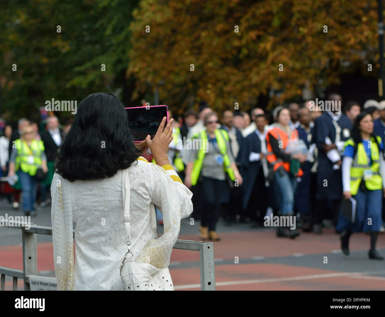 Marian Procession  Manchester, UK  05 October 2013 A woman on the pavement photographs an estimated thousand Catholics walking through South Manchester, praying the rosary and singing hymns as a visible expression of their faith. The procession starts at St Edward's Church, Rusholme and goes along Wilmslow Road to Fallowfield before going into Platts Fields Park for a short service. Credit:  John Fryer/Alamy Live News Stock Photo