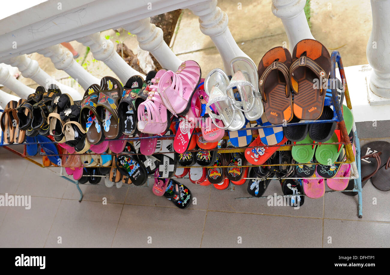 Children's shoes placed in a storage rack at a Vietnamese village infant school. Stock Photo