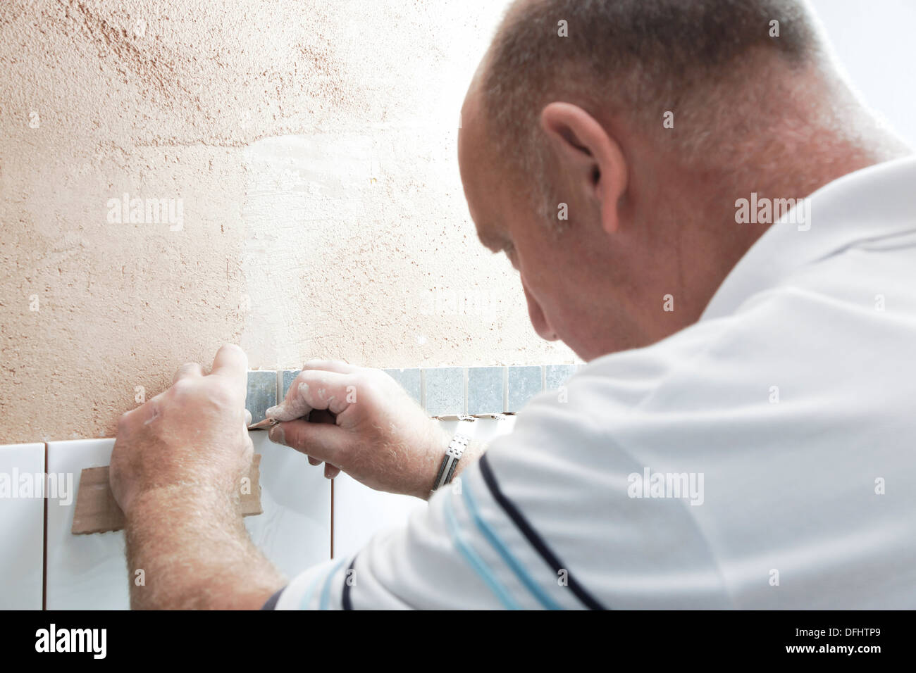 Tiler attaching tiles in a wet room / shower / bathroom on a newly plastered wall Stock Photo