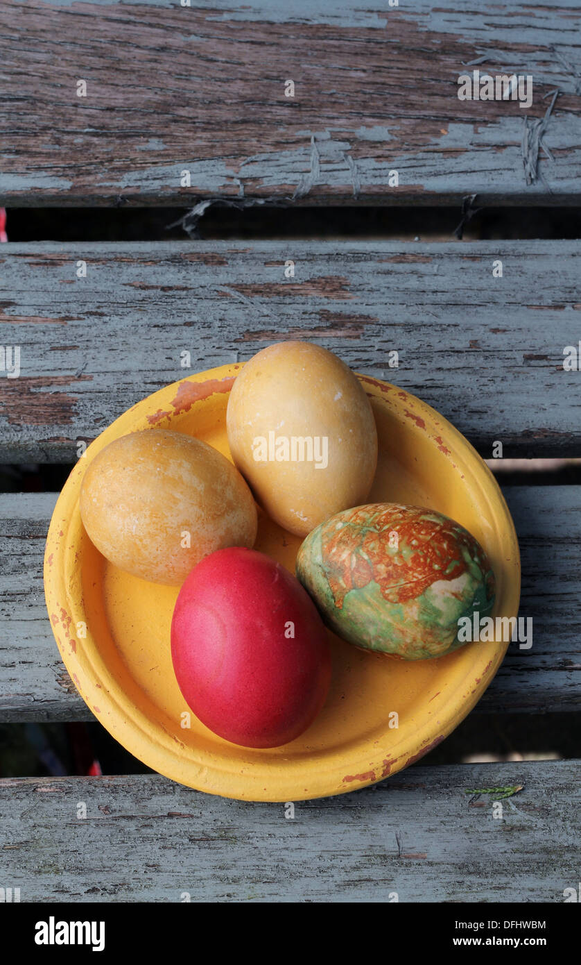 Vintage easter, four hand-painted eggs in an old yellow saucer on weathered , grunge wooden boards Stock Photo
