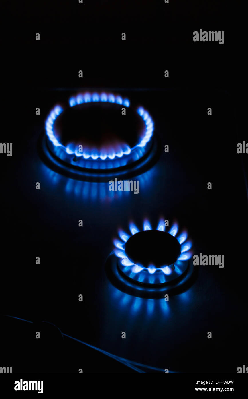 Gas hob cooker flames glowing ablaze in the dark Stock Photo