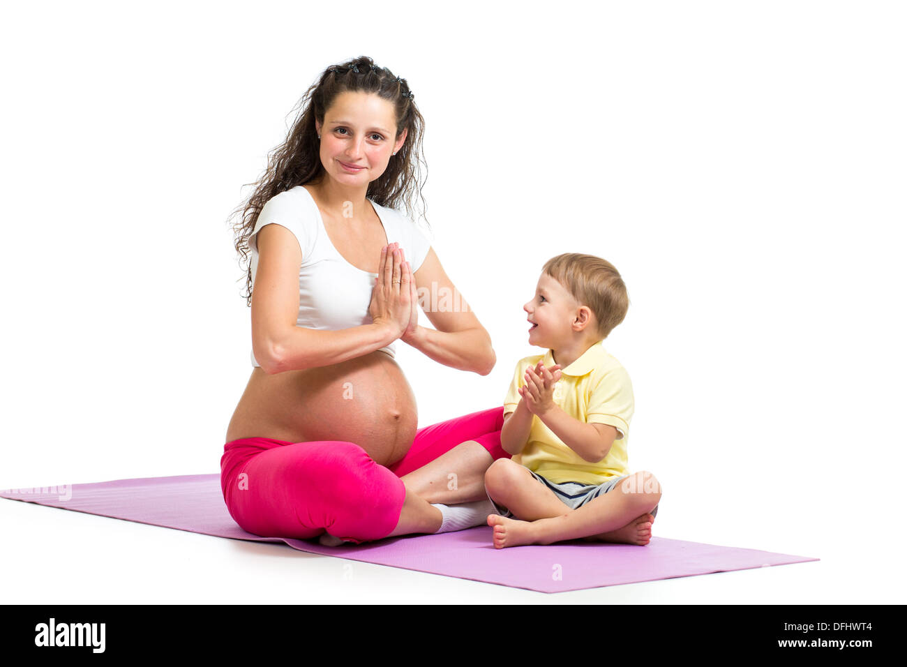 Pregnant woman relax doing yoga. Her son kid try to repeat exercises. Stock Photo