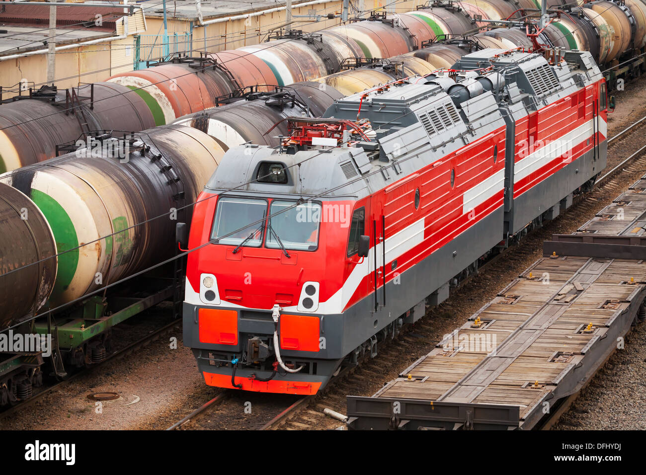 Modern red diesel electric locomotive rides on railway tracks with freight coaches Stock Photo