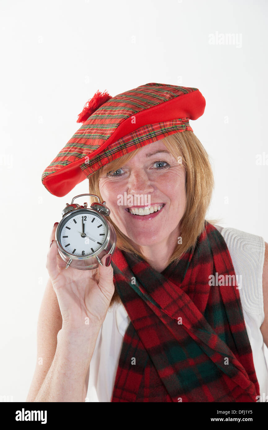 Woman celebrating the New Year as midnight strikes on her clock Stock Photo