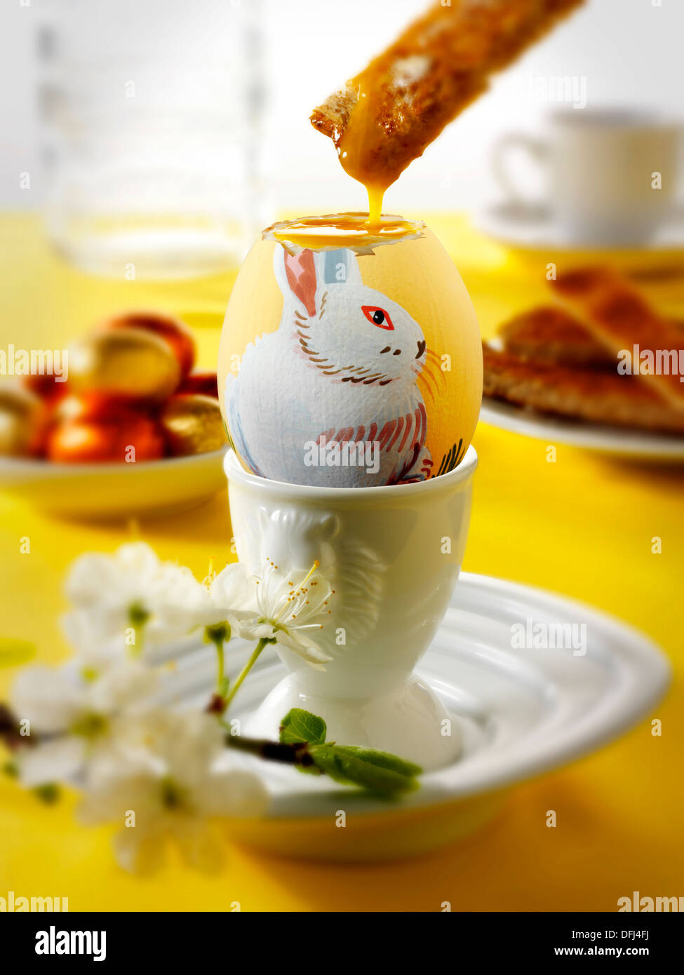 Traditional hand painted decorated boiled easter eggs in a breakfast setting with toast being dipped into the egg Stock Photo