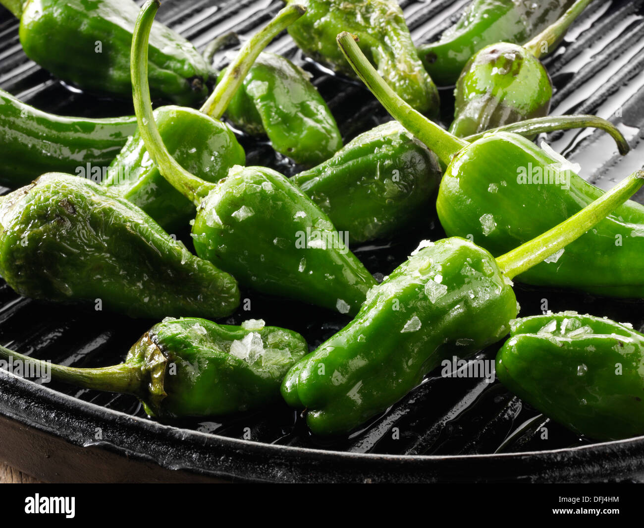 Cooked grilled patron peppers, or hebron peppers, on a black griddle, close up food photo still life Stock Photo