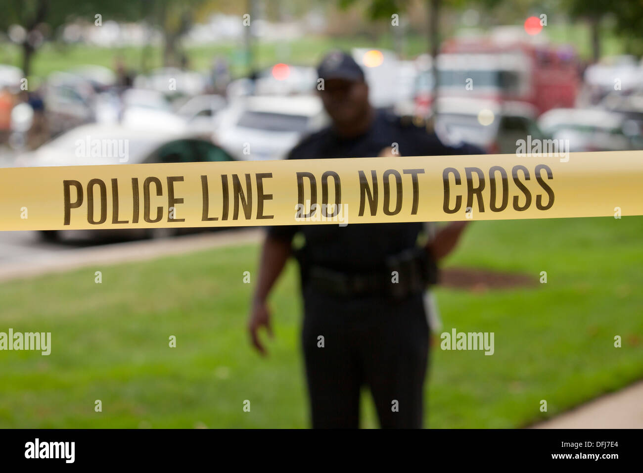 Policeman standing behind police line tape at a crime scene - Washington, DC USA Stock Photo