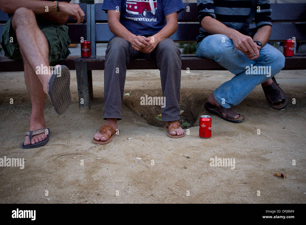 Three young men sitting on a bench and drinking beer in Barcelona, Spain. Stock Photo