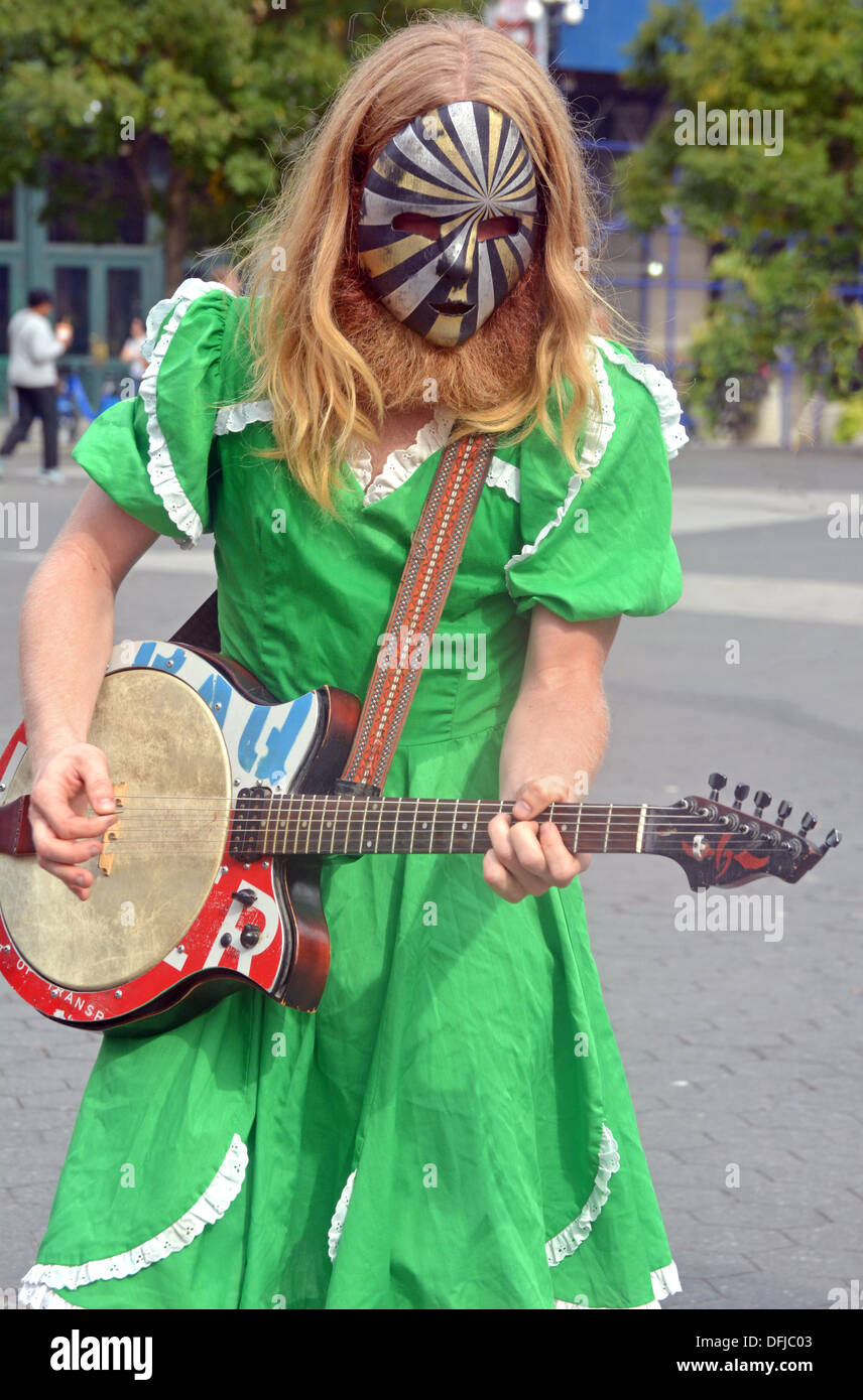 A street performing man with a beard in a dress wearing a mask in Union Square Park, New York City Stock Photo