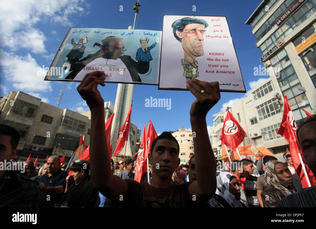 Ramallah, West Bank, Palestinian Territory. 6th Oct, 2013. A palestinian man holds a caricature of US Secretary of State John Kerry and a poster with the image of Israeli Prime Minister Benjamin Netanyahu holding up two hand puppets, US President Barack Obama (L) and US Secretary of State John Kerry (R) during a protest by hundreds of Palestinians in the West Bank city of Ramallah, on October 6, 2013, calling on Palestinian president Mahmud Abbas to withdraw from negotiations with Israel. Speaking before the UN General Assembly last week, Abbas warned the United Nations that US-brokered peace Stock Photo