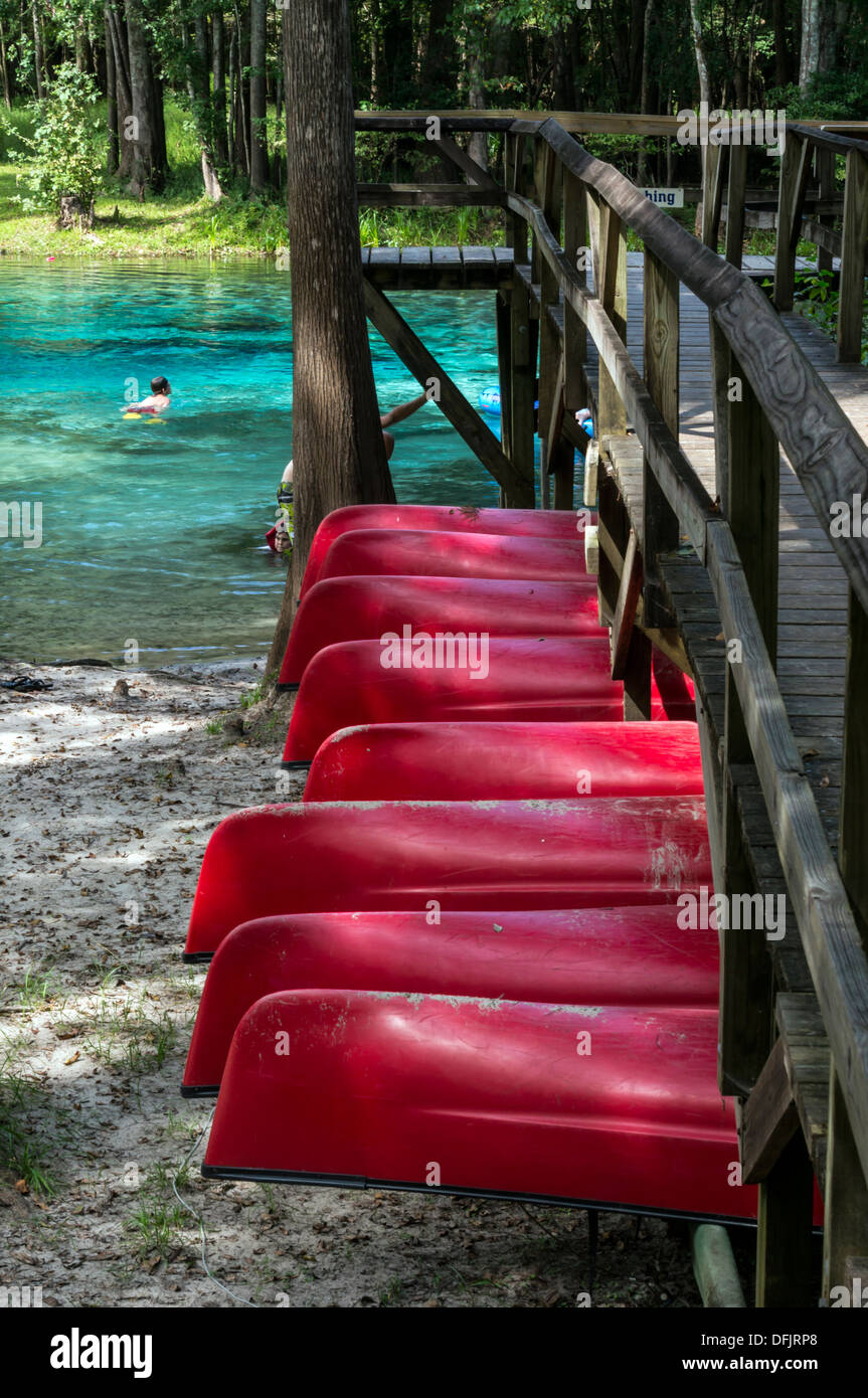 Red rental canoes, stacked below elevated wooden boardwalk at Blue