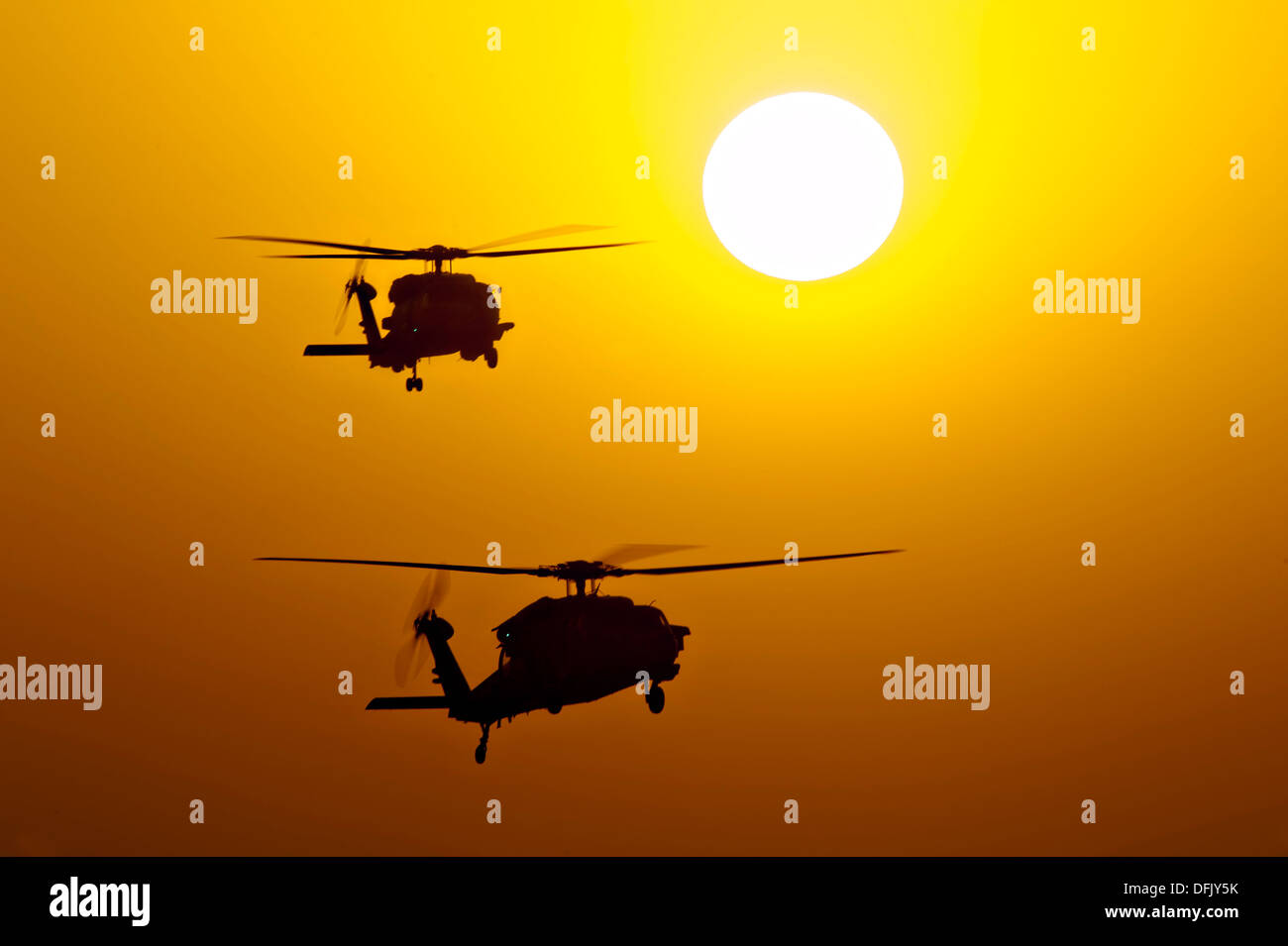US Navy MH-60S Knighthawk helicopters are silhouetted by the setting sun as they patrol near the aircraft carrier USS Harry S. Truman operating October 3, 2013 in the Gulf of Oman. Stock Photo