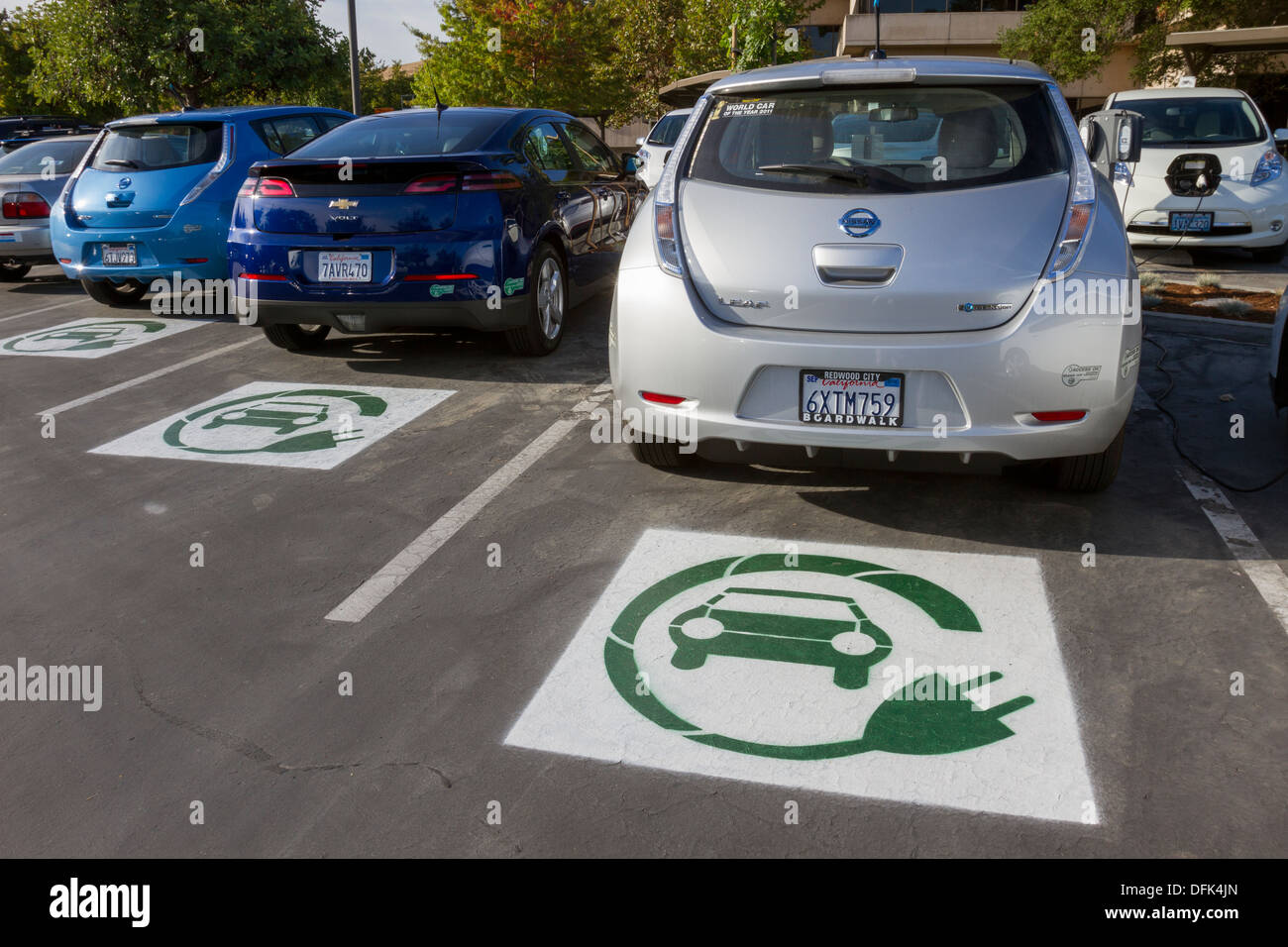 EV symbol painted on parking spaces in a company parking lot indicating spots are reserved for plug-in electric cars Stock Photo