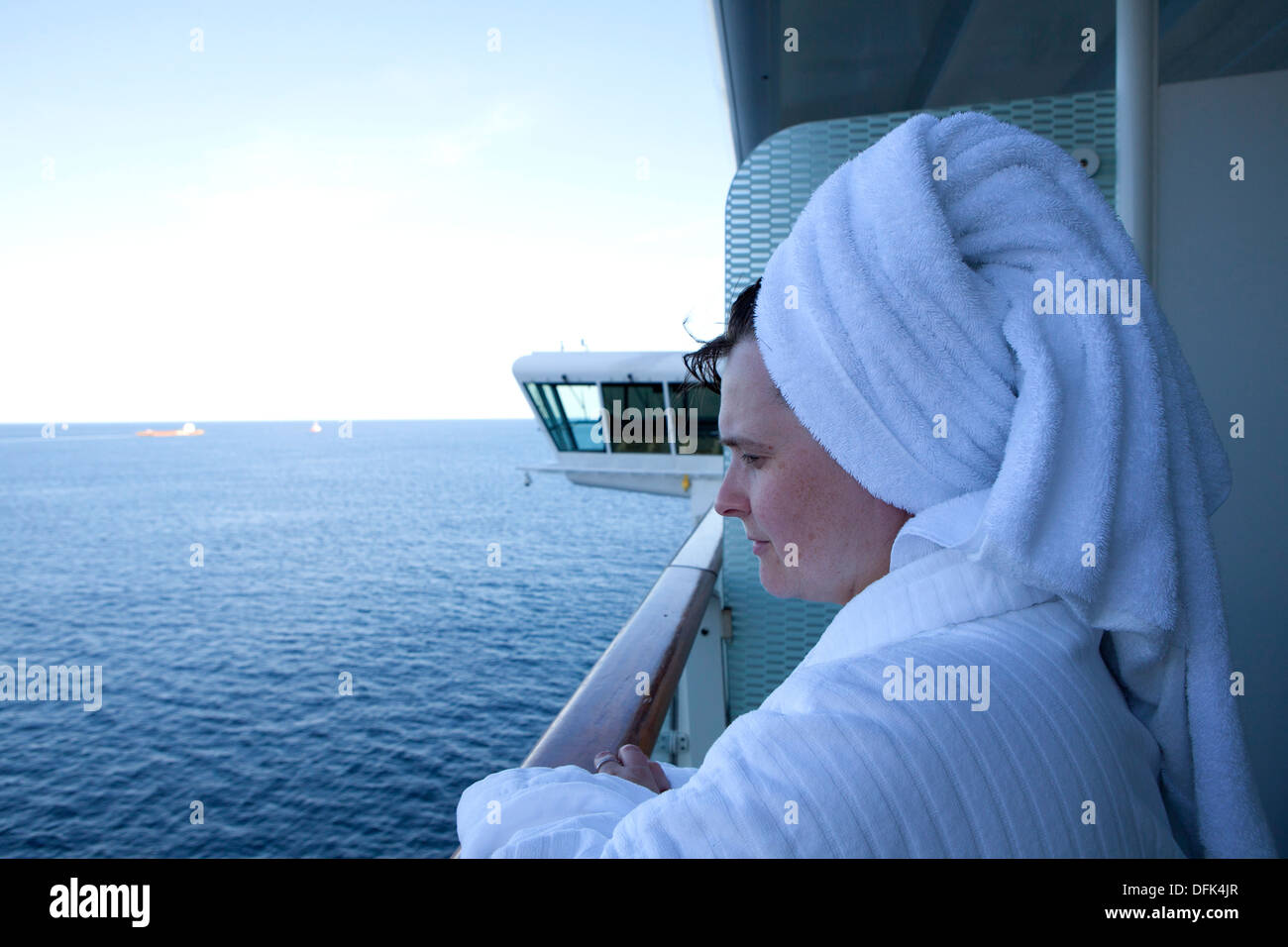 Woman in dressing gown and towel looking out to sea while on a cruise ship balcony Stock Photo