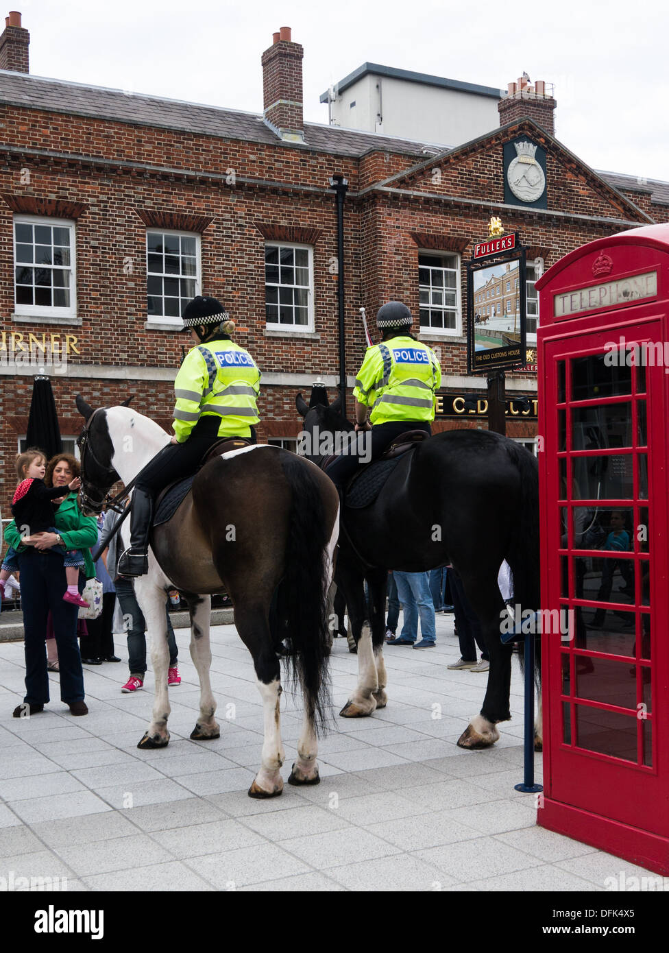 Two mounted police officers on horseback in front of a typical English pub and a red telephone box Stock Photo