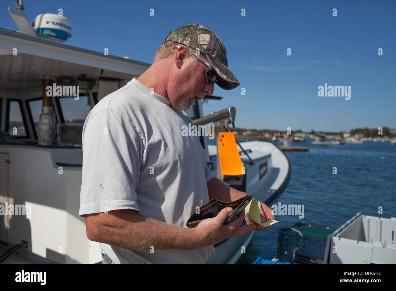 Lobsterman Peter Wildes on lobster dock in Maine gets paid for selling