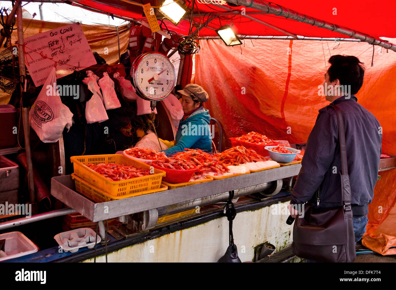 Asian woman weighing a bag of prawns for a customer at a fish market at Fisherman's Wharf, Steveston, British Columbia, Canada. Stock Photo