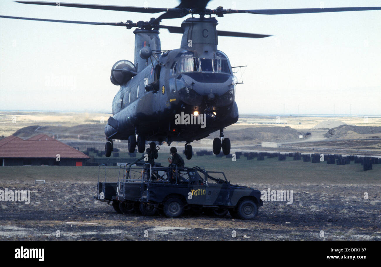 An RAF Boeing Chinook helicopter about to lift a trio of old Land Rovers in the Falkland Islands Stock Photo