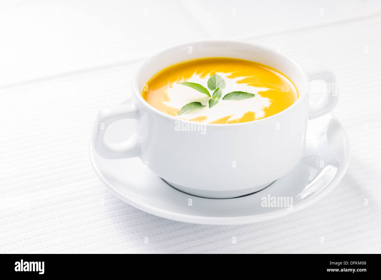 Pumpkin soup with basil on served table Stock Photo