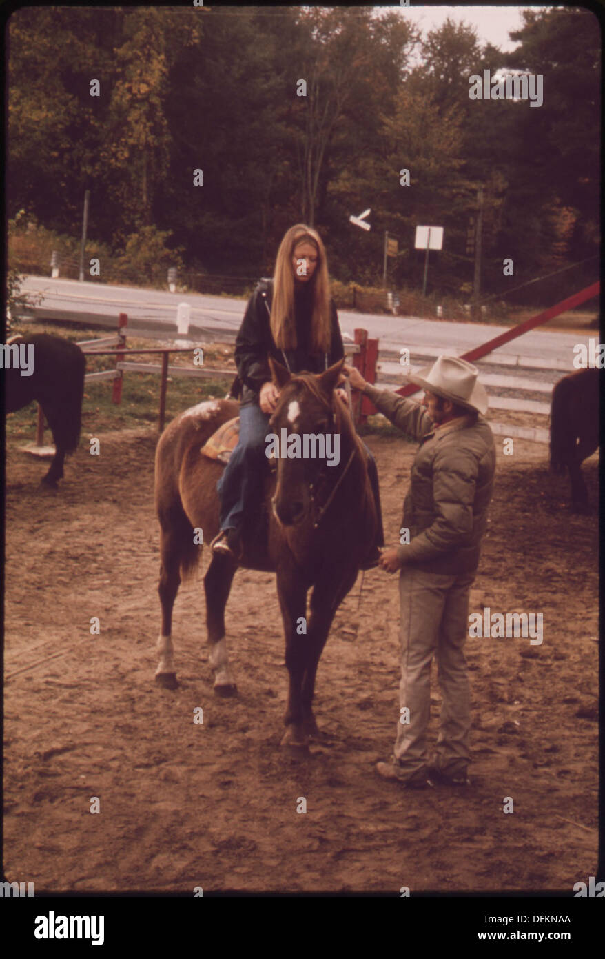 LOCAL COWBOY HELPS A RIDER GET READY FOR A FALL MORNING TRAIL RIDE AT THE SIT 'N BULL RANCH IN THE ADIRONDACK FOREST... 554689 Portrait Stock Photo