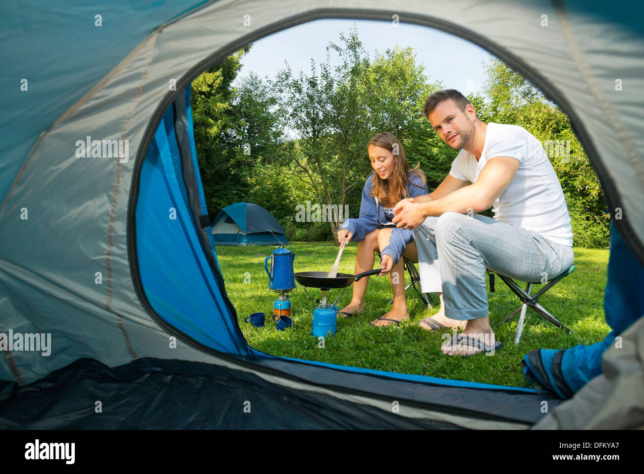A young couple cooking in front of a tent Stock Photo