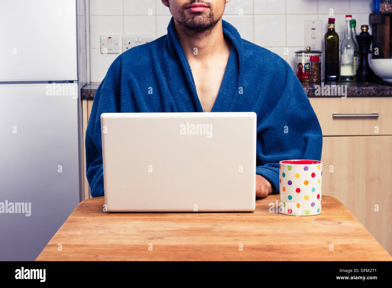 Young man using laptop in kitchen Stock Photo