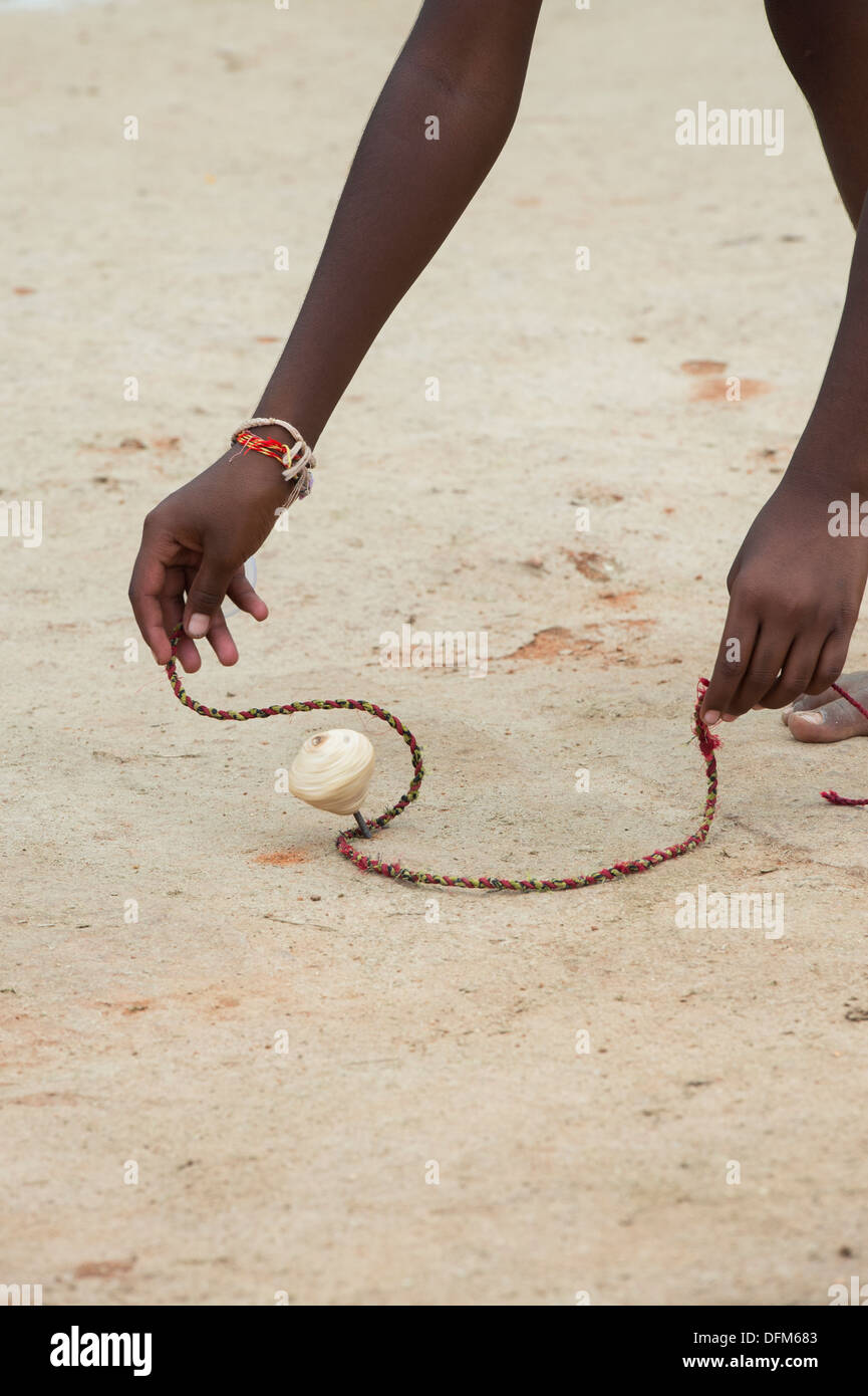 Rural Indian village boy playing with wooden spinning top toy. Andhra