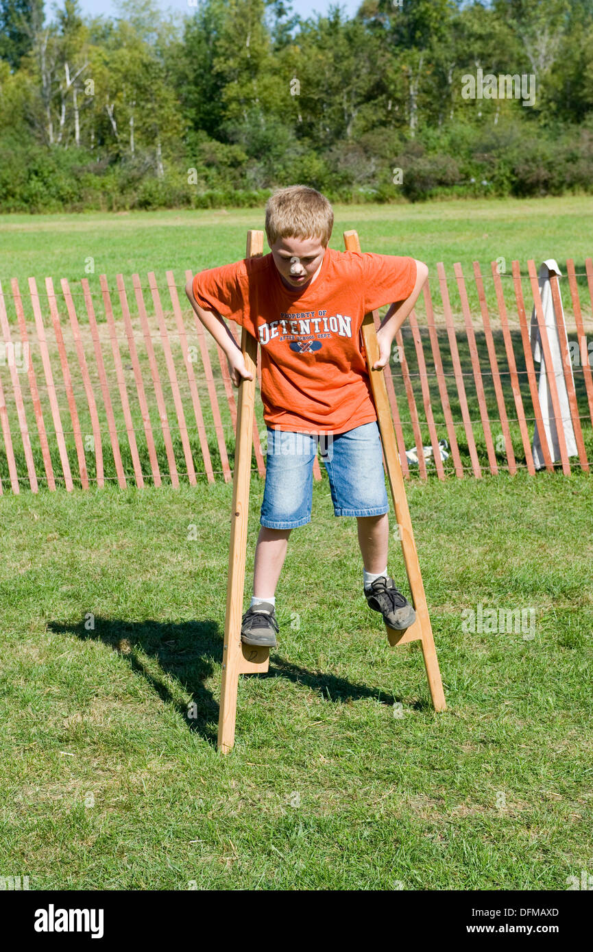 Child walking on wooden stilts learning how to balance on an object