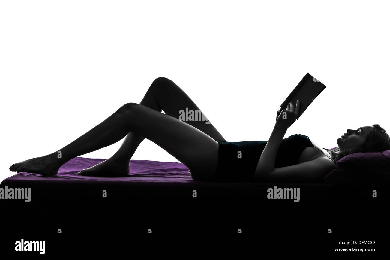 one woman lying reading book in bed silhouette studio on white background Stock Photo