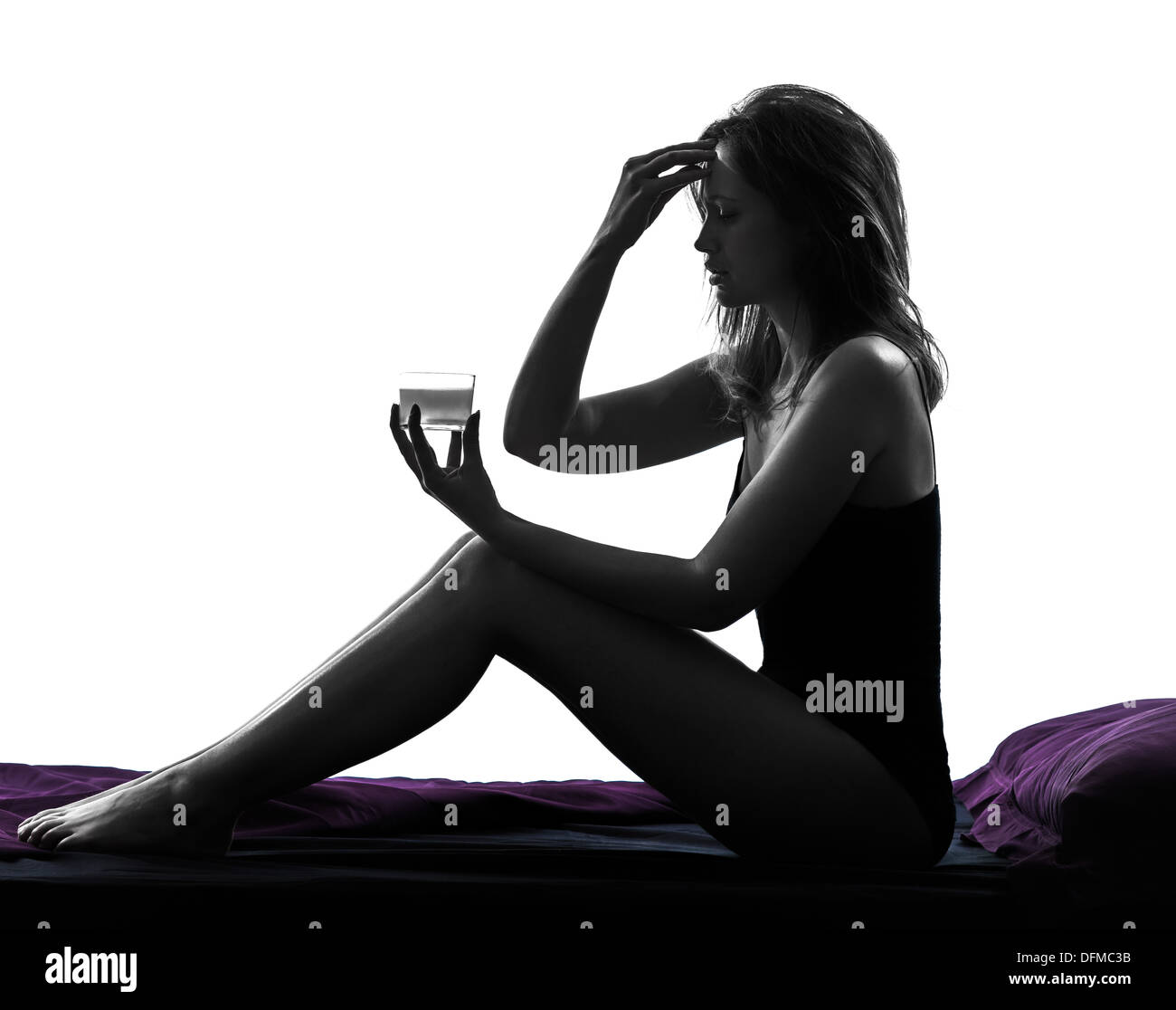 one woman headache sitting in bed taking medicine silhouette studio on white background Stock Photo