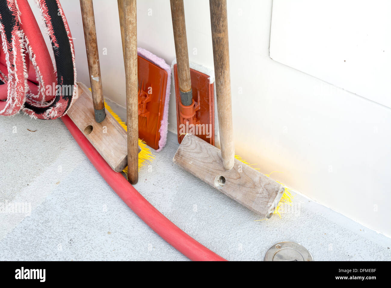 A set of boat deck cleaning and scrubbing supplies propped up against the hull Stock Photo