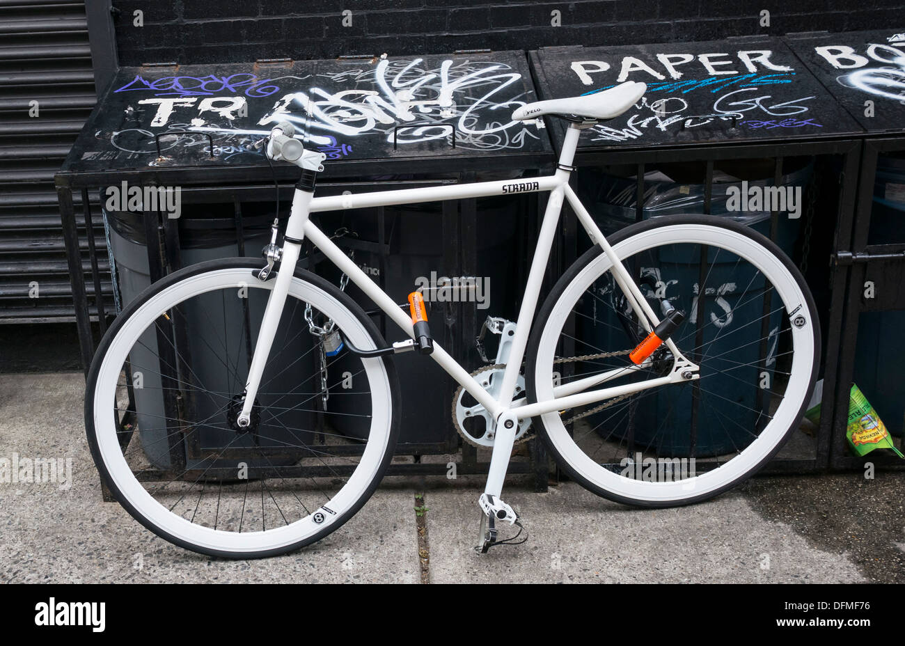 Clean white bike tied to garbage cans area in New York City Stock Photo