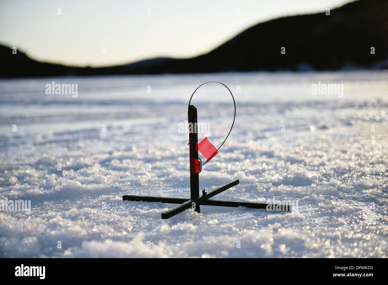 Silhouette of spring loaded ice-fishing hole marker on a frozen