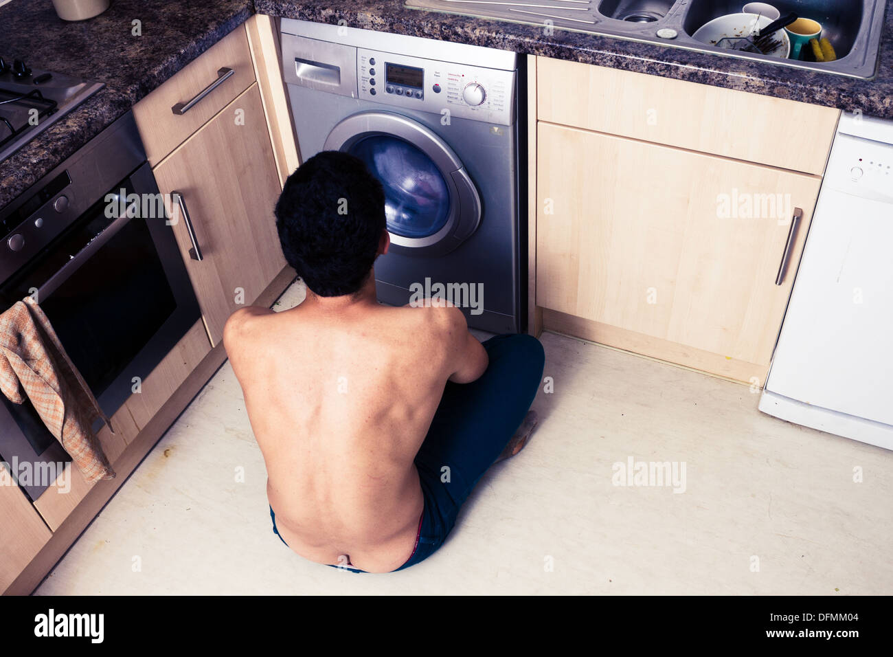 Young man watching his washing machine Stock Photo Alamy