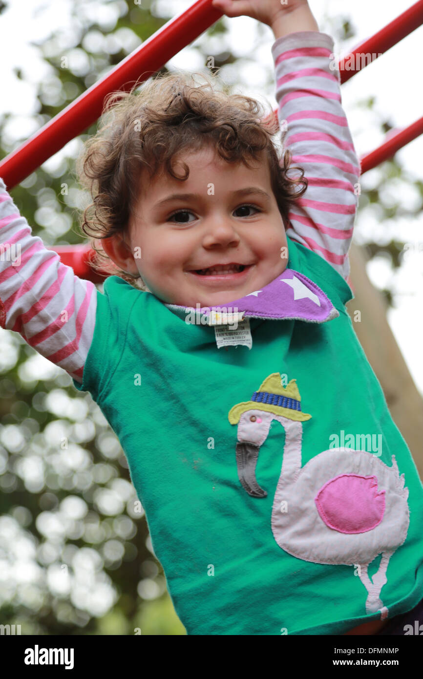 Toddler swinging from bars in the park Stock Photo Alamy