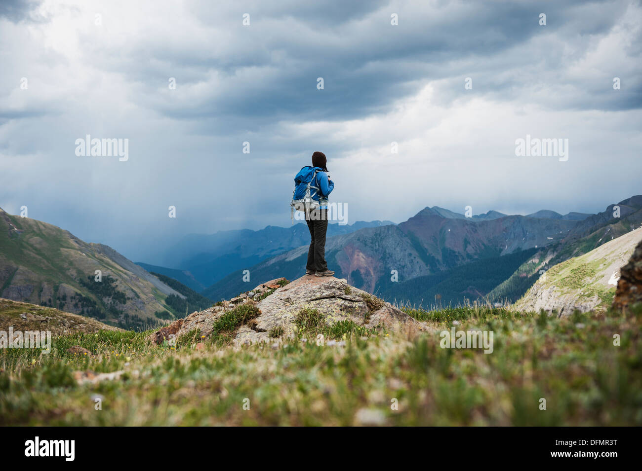 Female hiker watches approaching thunderstorms from Ice Lakes Basin, San Juan mountains, Colorado, USA Stock Photo