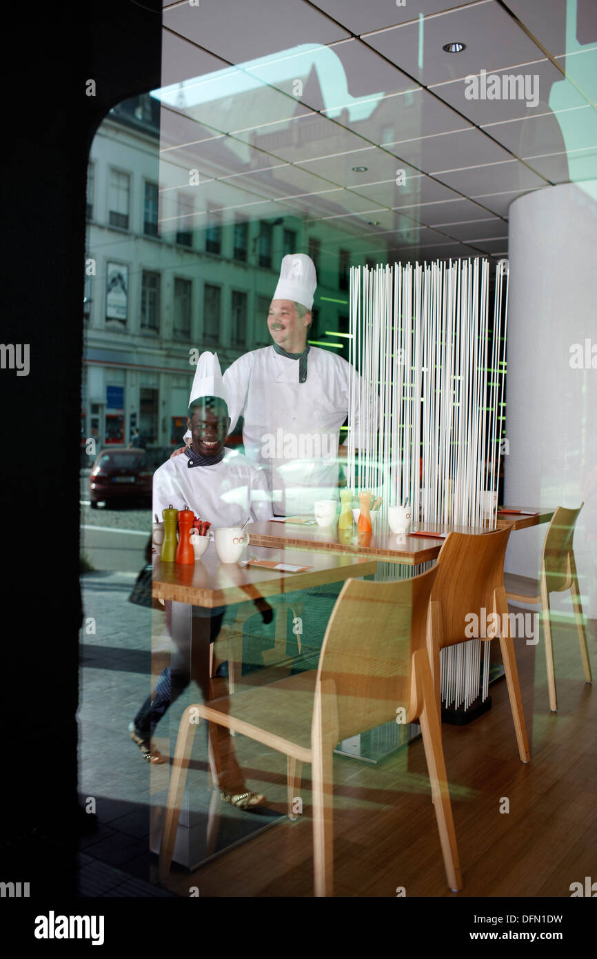 Cooks in the restaurant and reflection in the front window of Hotel BLOOM, Brussels, Belgium Stock Photo