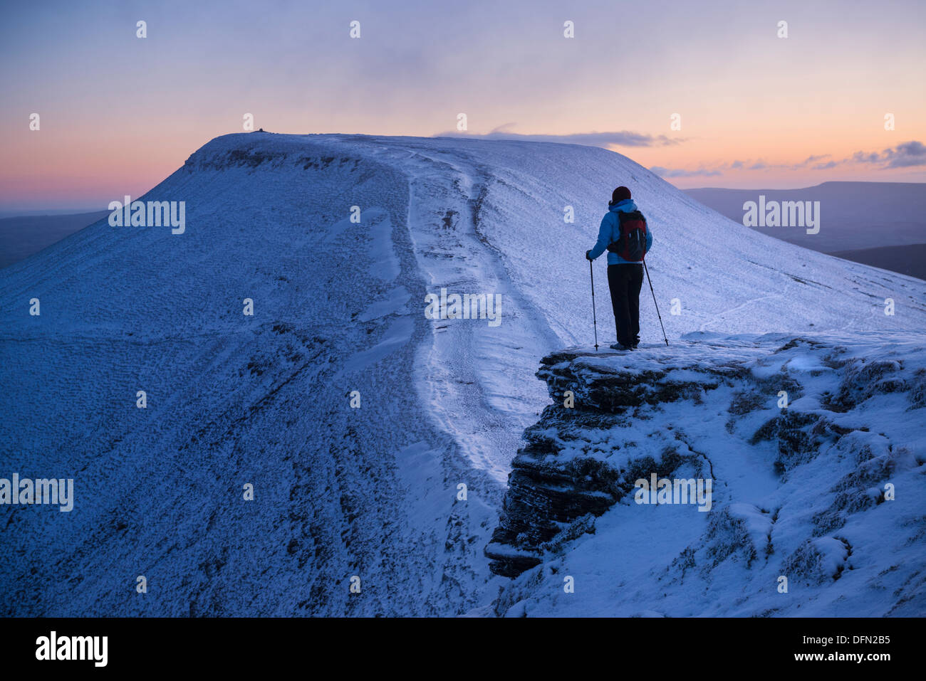 Female hiker looks towards Pen Y Fan at dawn from Corn Du, Brecon Beacons national park, Wales Stock Photo