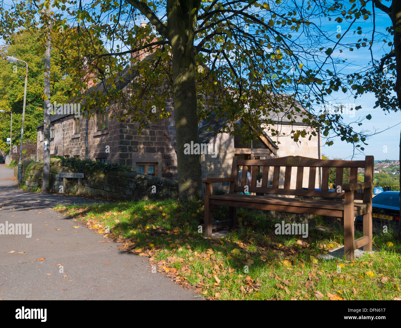 Wooden Bench next to a tree in the village of Holbrook, Derbyshire, United Kingdom. Stock Photo