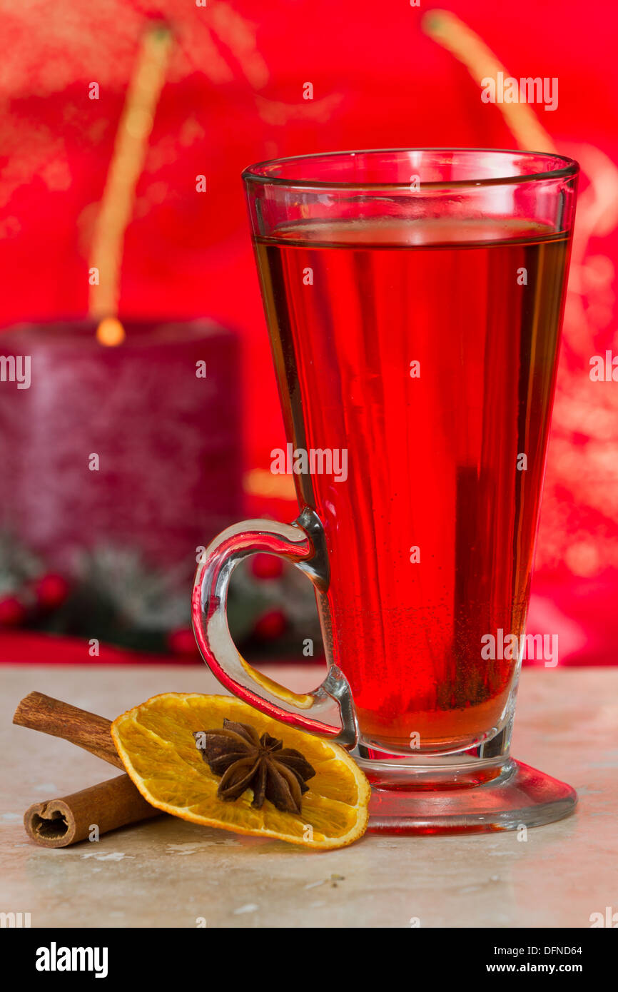 christmas morning tea served in a tall clear glass with spices and a red table cloth Stock Photo