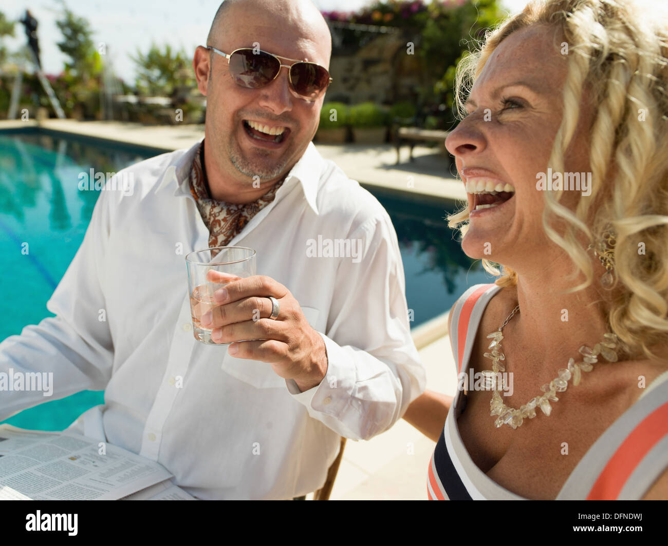 A Young man enjoys his drink with a beautiful woman by the side of a swimming pool in San Diego. Stock Photo