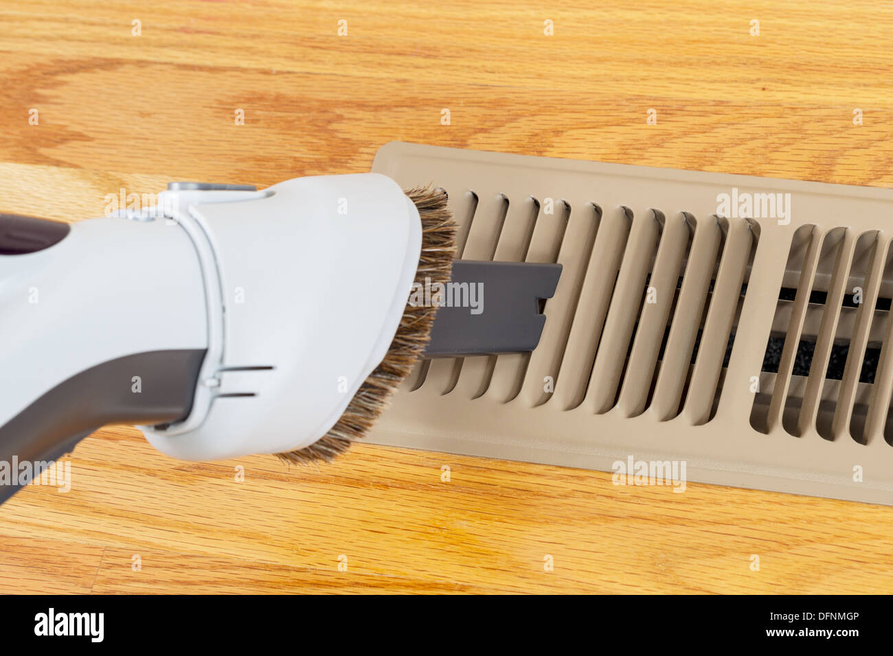 Horizontal photo of vacuum cleaning heater floor vent with Red Oak Floors in background Stock Photo